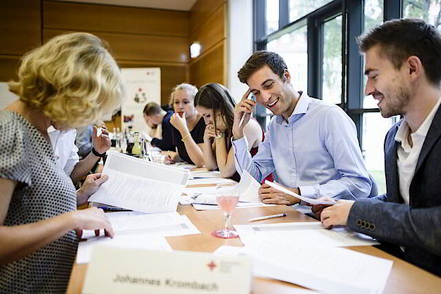Verschiedene Menschen sitzen an einem Besprechungstisch