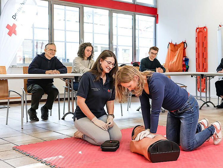 Eine Junge Frau übt unter Anleitung einer Ausbilderin die Herzmassage
