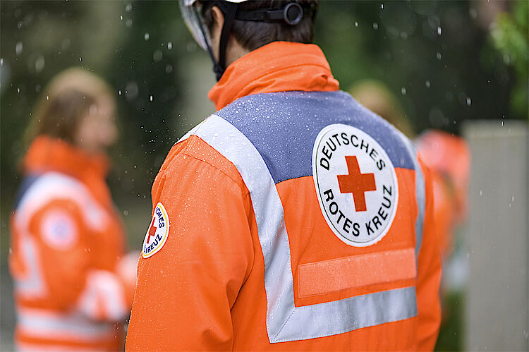 Mitarbeiter vom DRK in Einsatzjacke bei Regen Mitarbeiter vom DRK in Einsatzjacke bei Regen