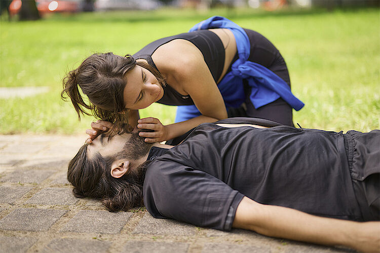 Sportlerin macht bei einem Mann im Freien Wiederebelegungsmaßnahmen