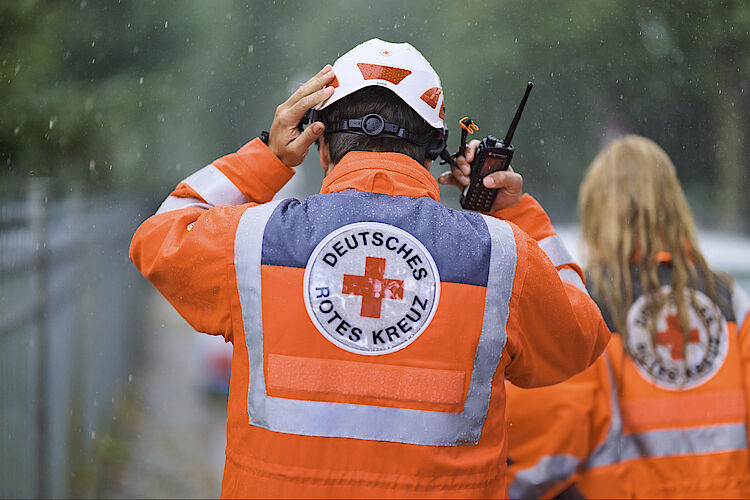 Srechfunker im Regen Zwei Sanitäter laufen mit Funkgerät im Regen